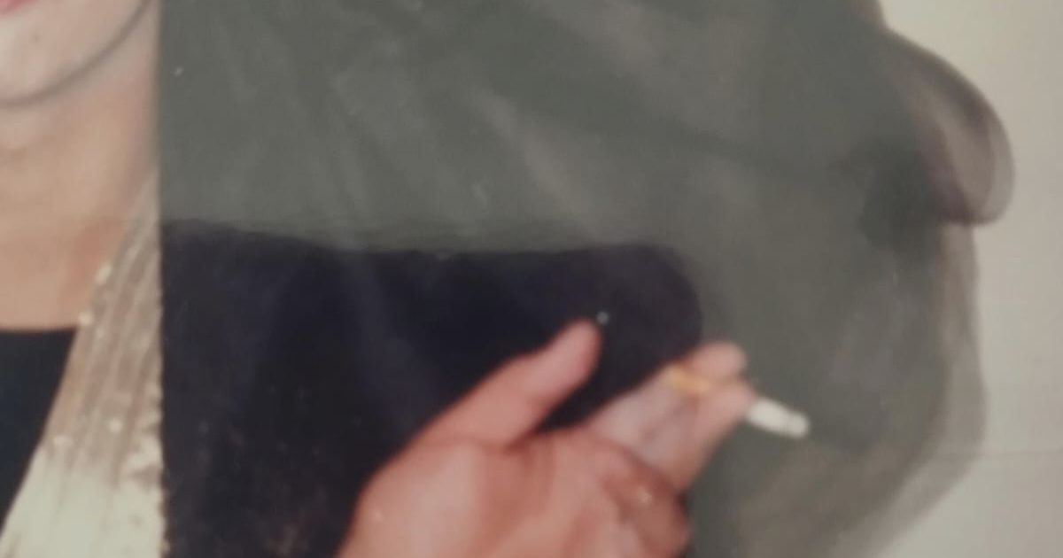 Mara b’libsa tad-deheb, xagħarha goff, u b'sigarett.