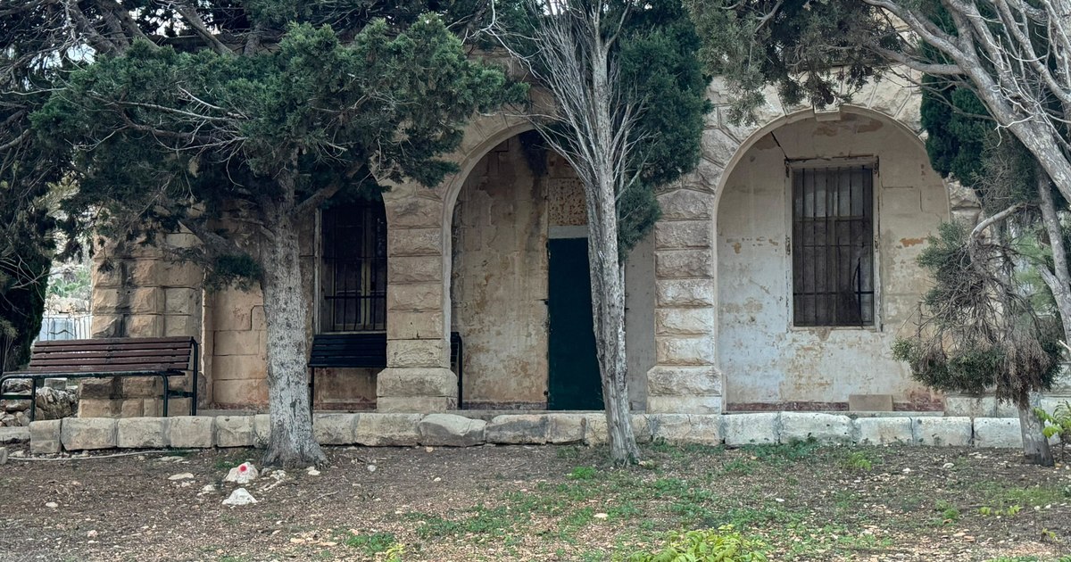 Kamra tal-ġebel bl-arkati, siġar u ħaxix quddiema.